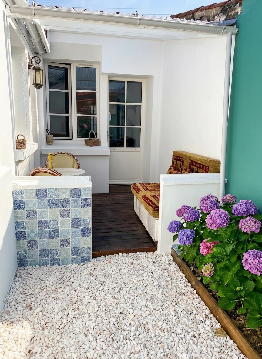 Remove the blue and white ceramic flower pot on the left side of the image, replacing it with the white gravel ground that surrounds it. Keep everything else exactly the same: the tiled wall, the wooden deck, the outdoor seating with cushions, the hydrangeas on the right, the windows, the lantern, and the turquoise wall.